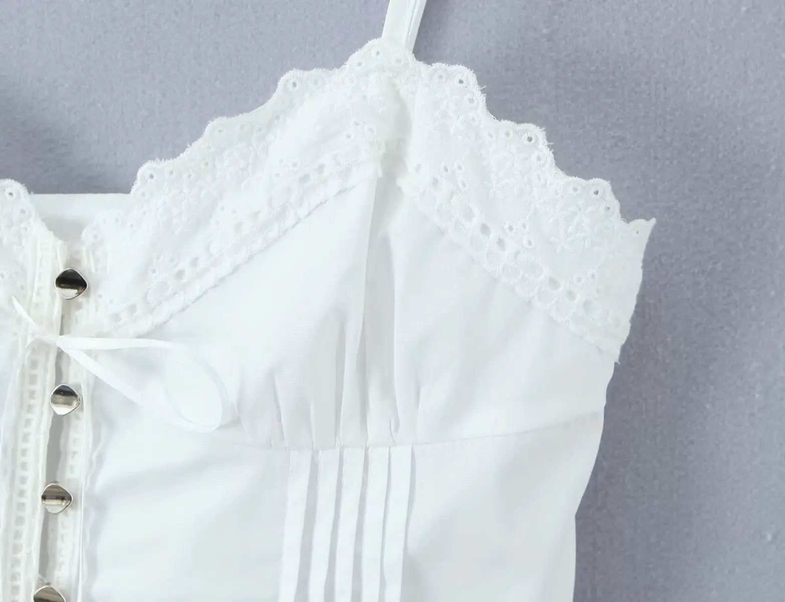 Close-up of scalloped lace trim at the bustline of white corset top