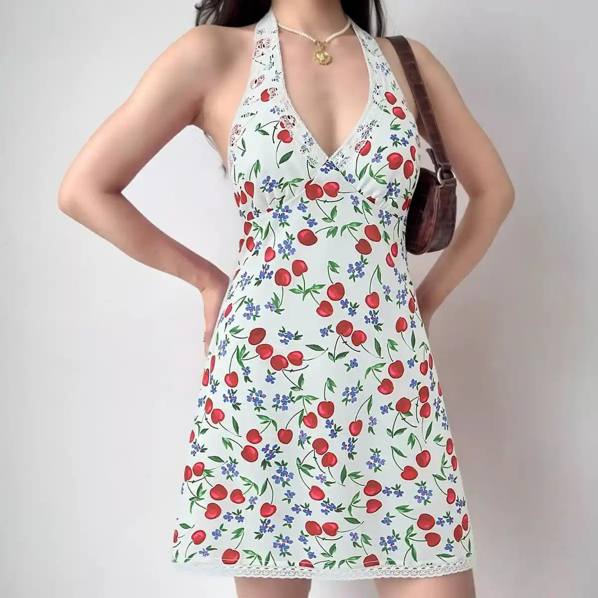 Model wearing white cherry print halter-neck mini dress with lace trim, vintage-inspired summer dress