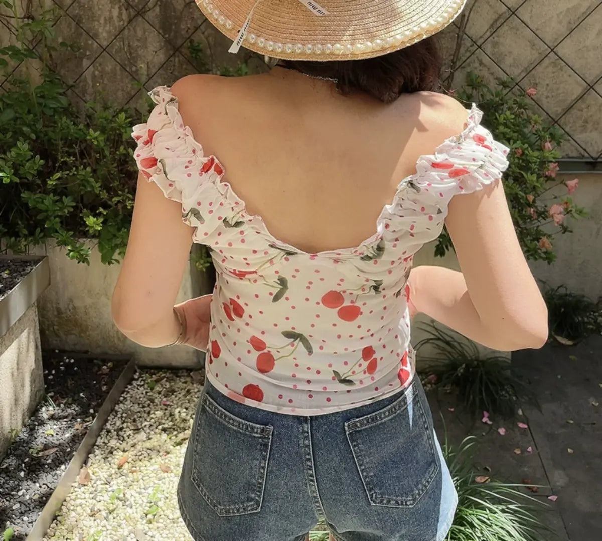Back view of white cherry print off-shoulder top with fitted silhouette and ruffled shoulder straps