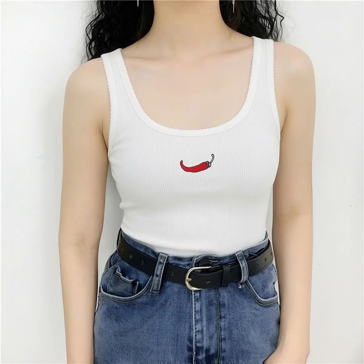 Model wearing white ribbed tank top with red chili pepper embroidery and fitted silhouette