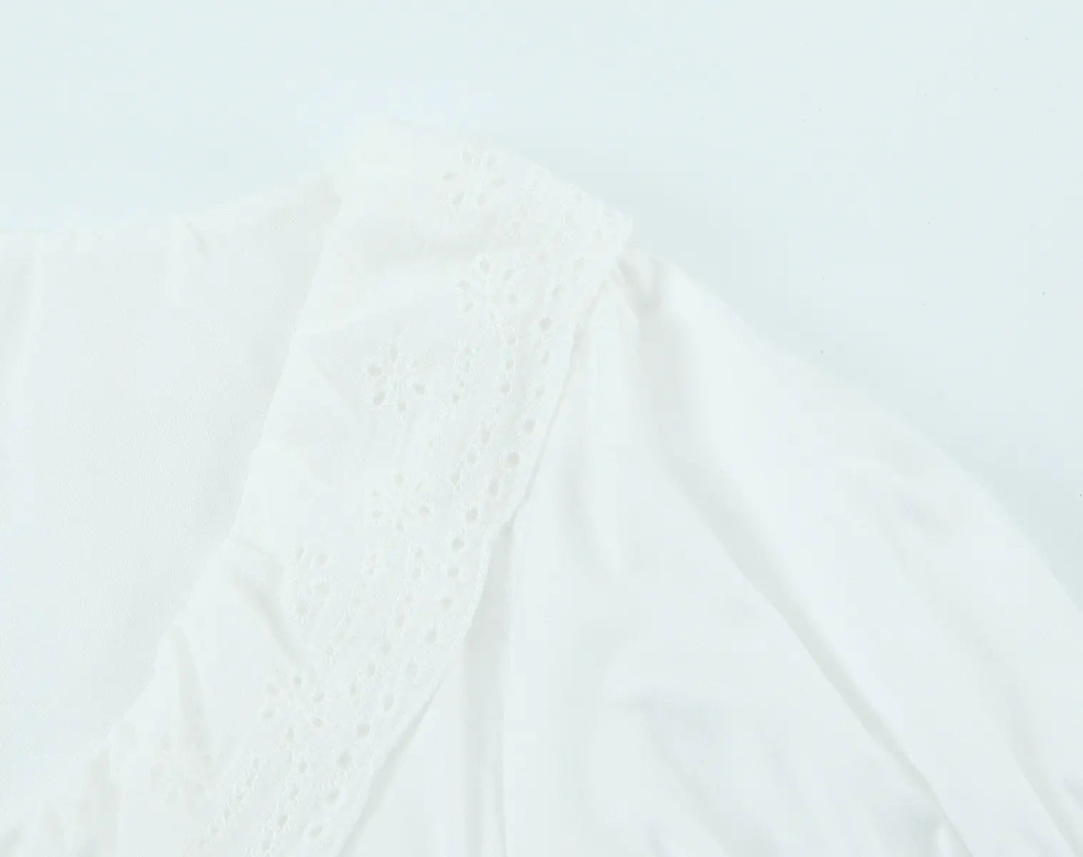 Close-up of eyelet lace trim on white keyhole crop top