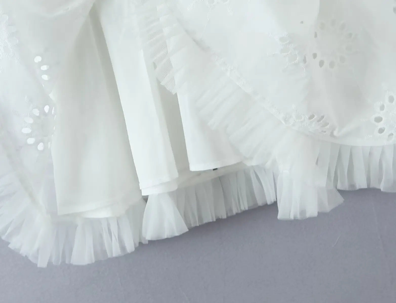 Close-up of layered ruffled hem and lining on white eyelet halter dress