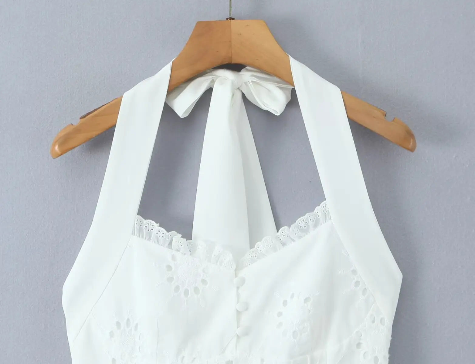 Close-up of halter neckline and tie closure detail on white eyelet dress