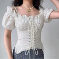 Model wearing white eyelet embroidered puff-sleeve corset top with lace-up back, vintage cottagecore bustier