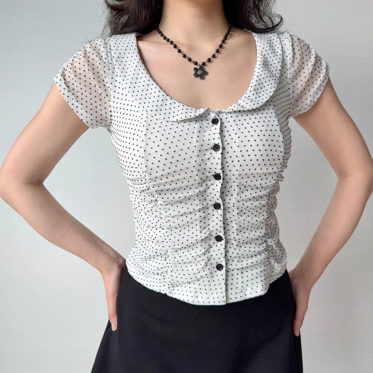 Front view of white eyelet lace top showing the rounded collar, puff sleeves, and fitted silhouette