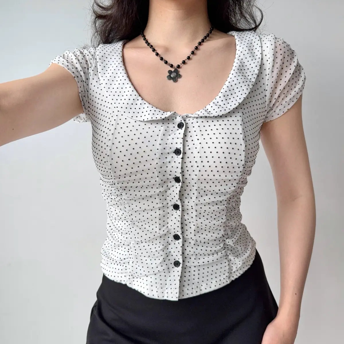 Outfit view of white eyelet lace top styled with black bottoms, highlighting the semi-sheer texture