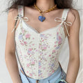 Model wearing white floral print cami corset top with lace trim and bow straps, romantic vintage-inspired top
