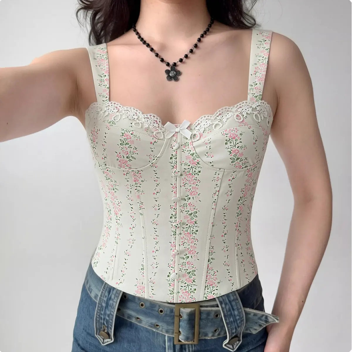 Model wearing white floral print corset-style cami top with lace trim and bow detail