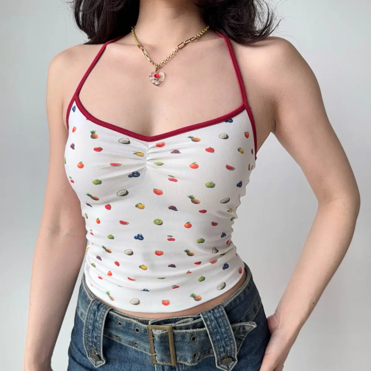 Model wearing white fruit-print halter-neck cami top with red trim, front ruched detail and fitted silhouette