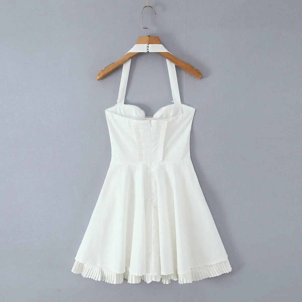 White halter corset dress hanging on wooden hanger, back view