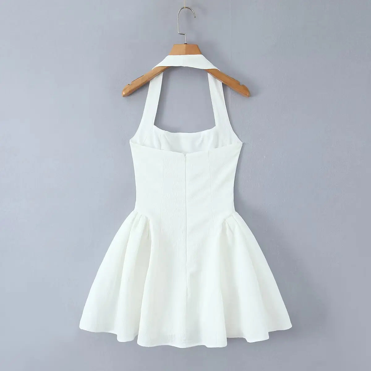 White halter mini dress hanging on wooden hanger, back view