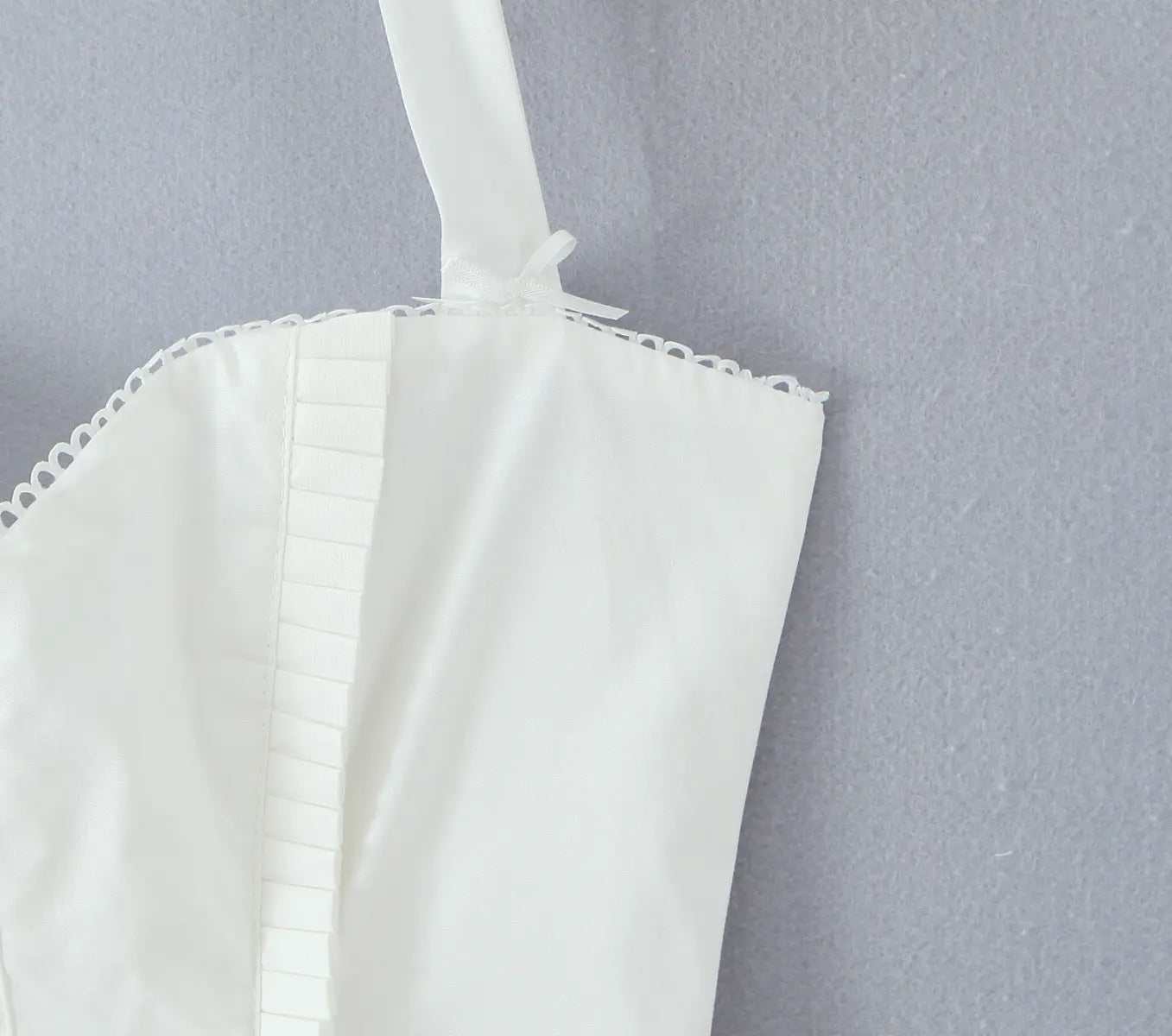Close-up of ruched back and strap detail on white halter corset dress