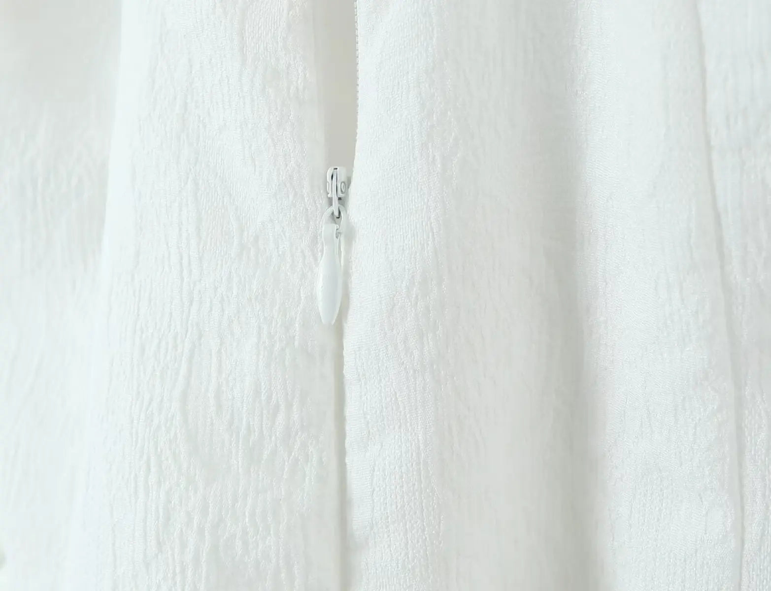 Close-up of textured fabric and back zipper on white halter dress