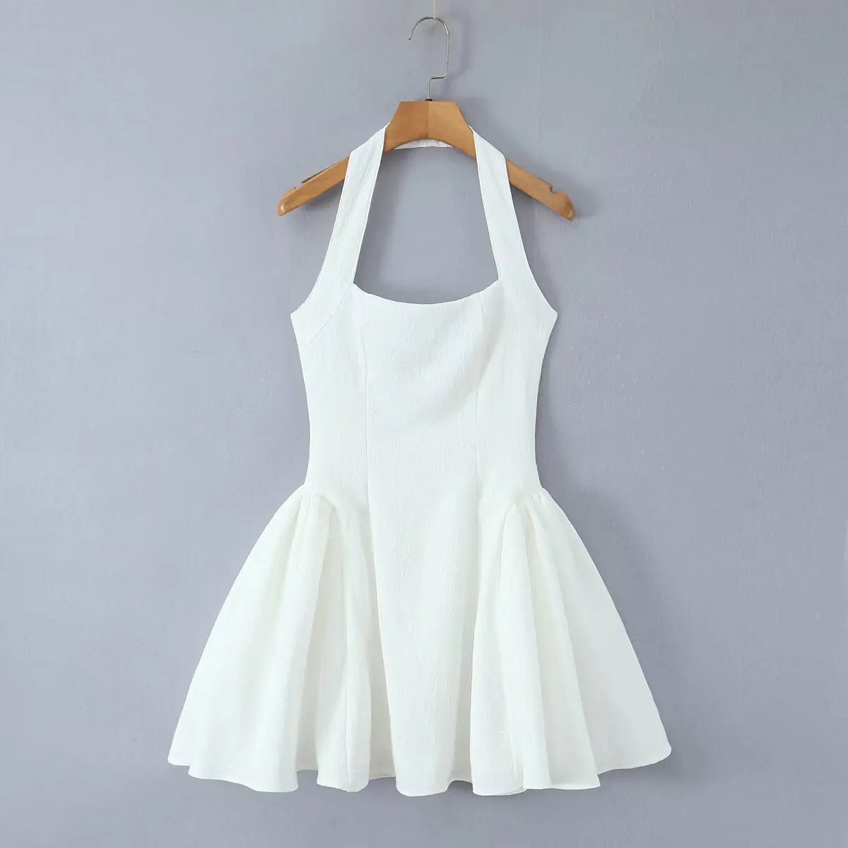 White halter mini dress hanging on wooden hanger, front view