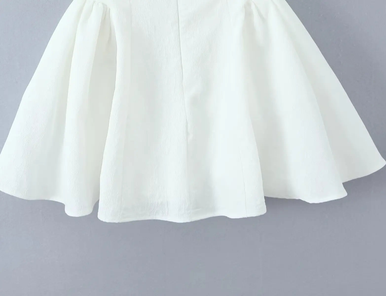 Close-up of flared ruffled hem on white halter mini dress