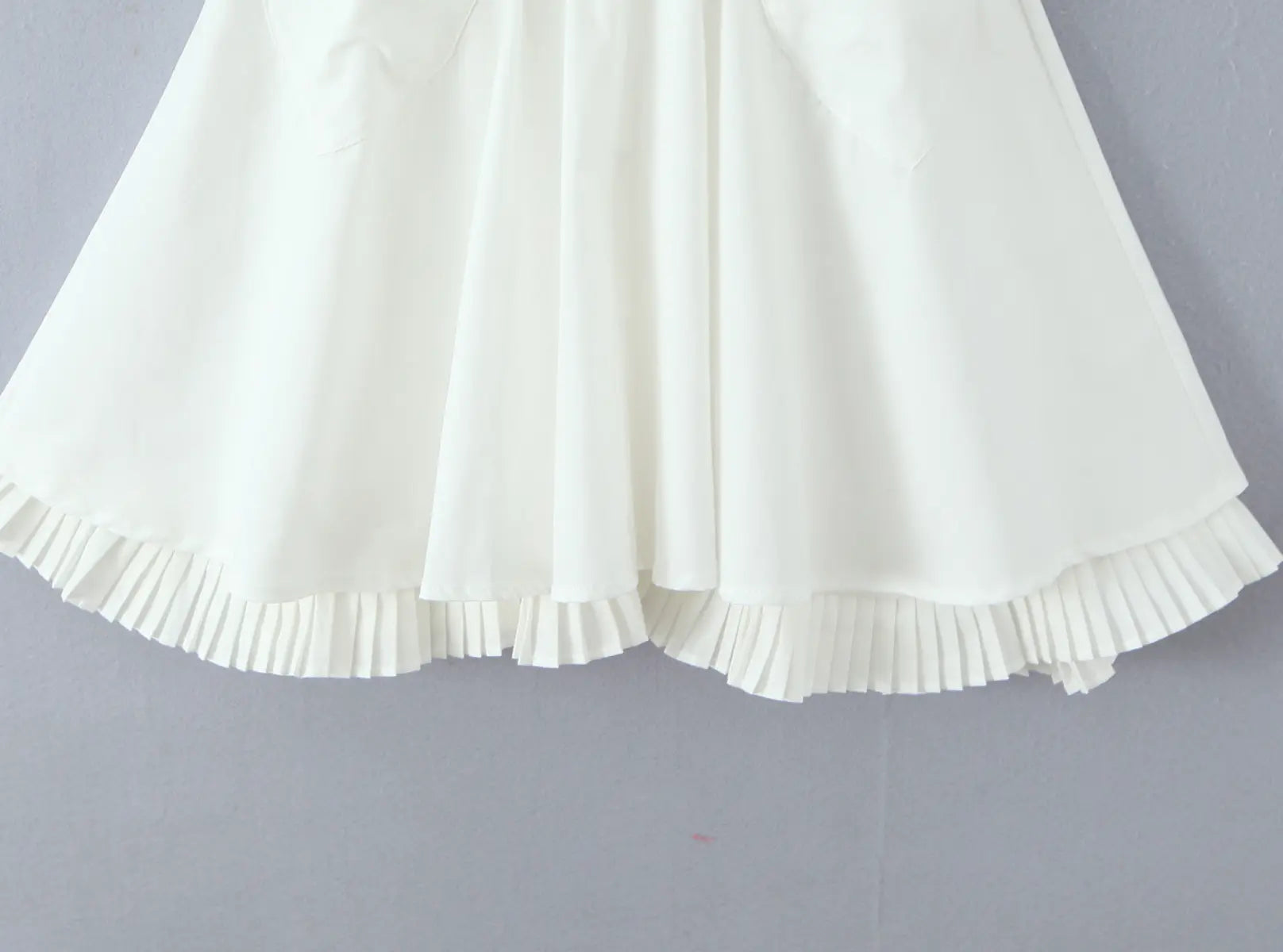 Close-up of ruffled hem detail on white halter mini dress