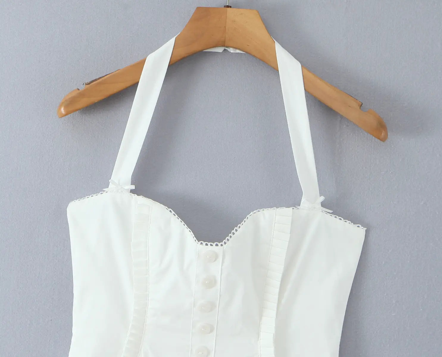 Close-up of sweetheart neckline and front button placket on white halter dress