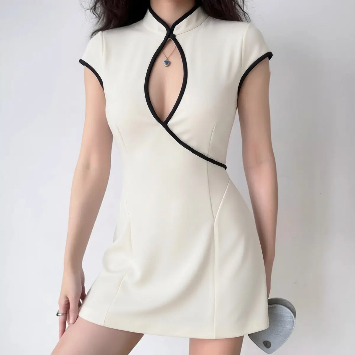 Model wearing white cheongsam-style dress with keyhole neckline and black trim, form-fitting mini dress