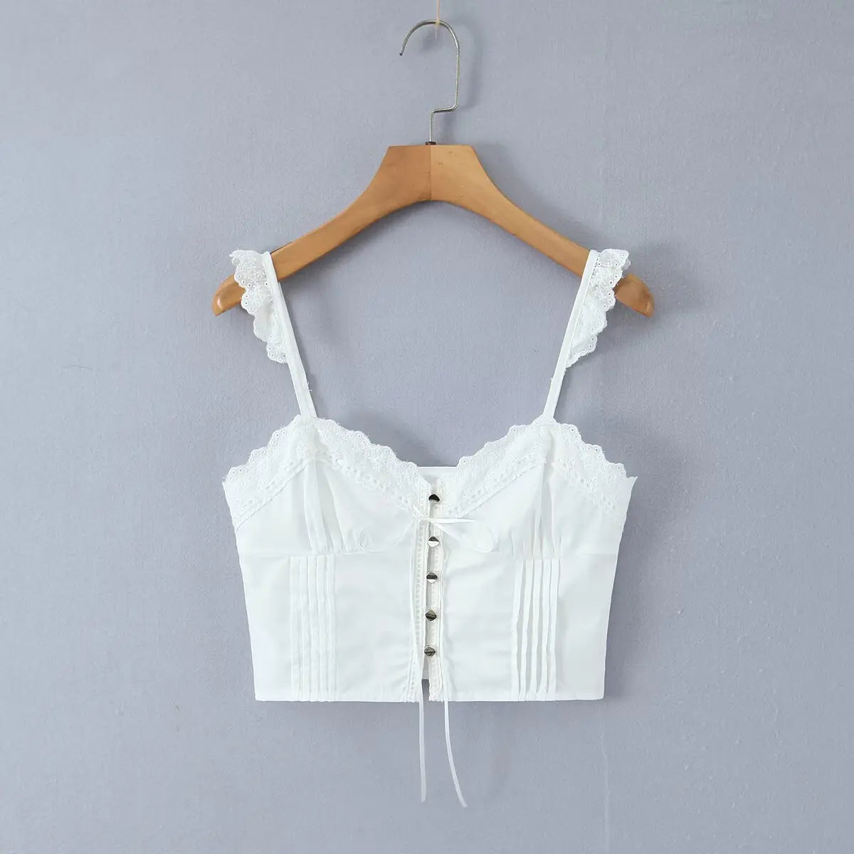 White lace cami corset top hanging on wooden hanger, front view