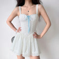 Woman wearing white lace cami mini dress with light blue ribbon detail, full front view