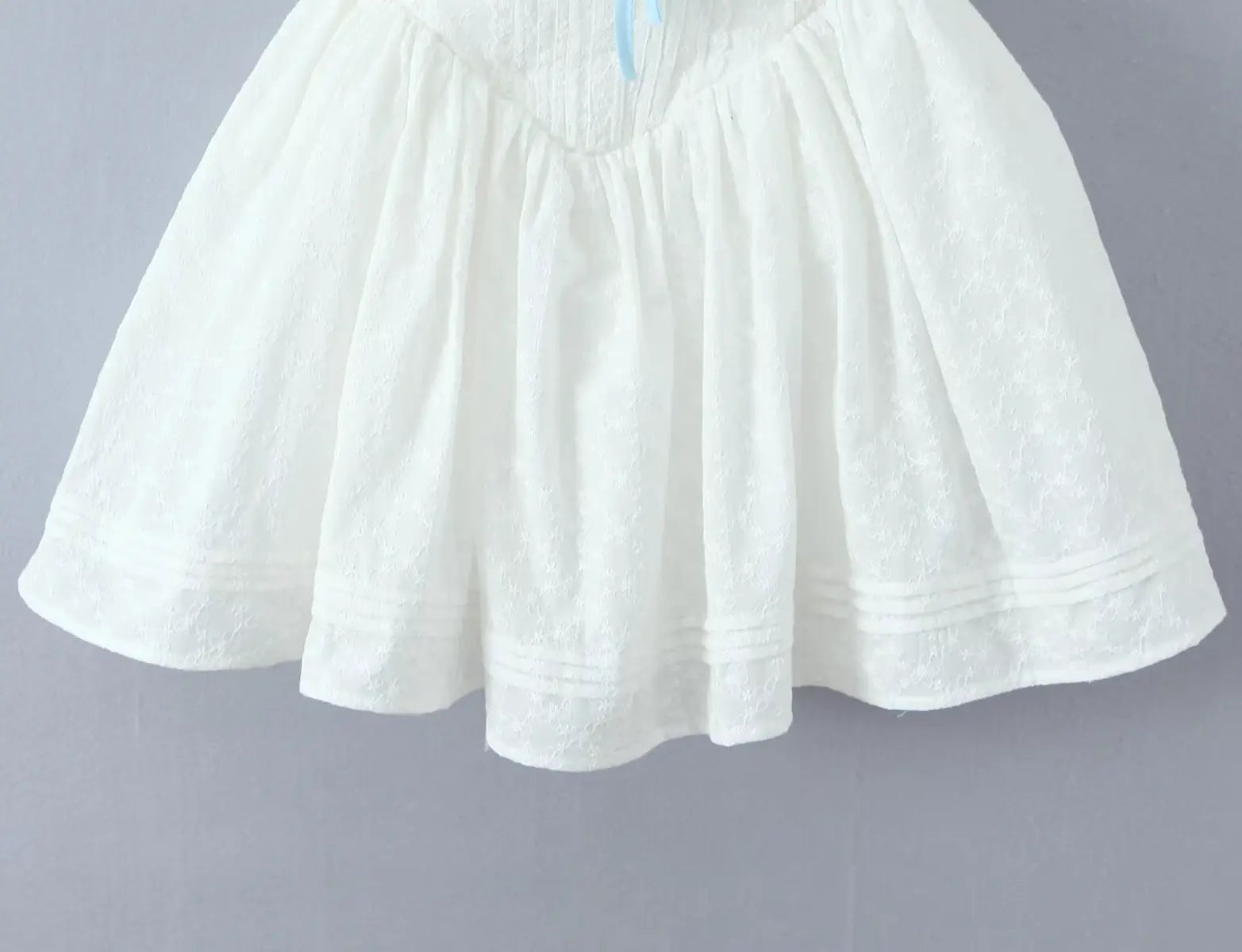 Close-up of flared ruffled hem on white lace cami dress
