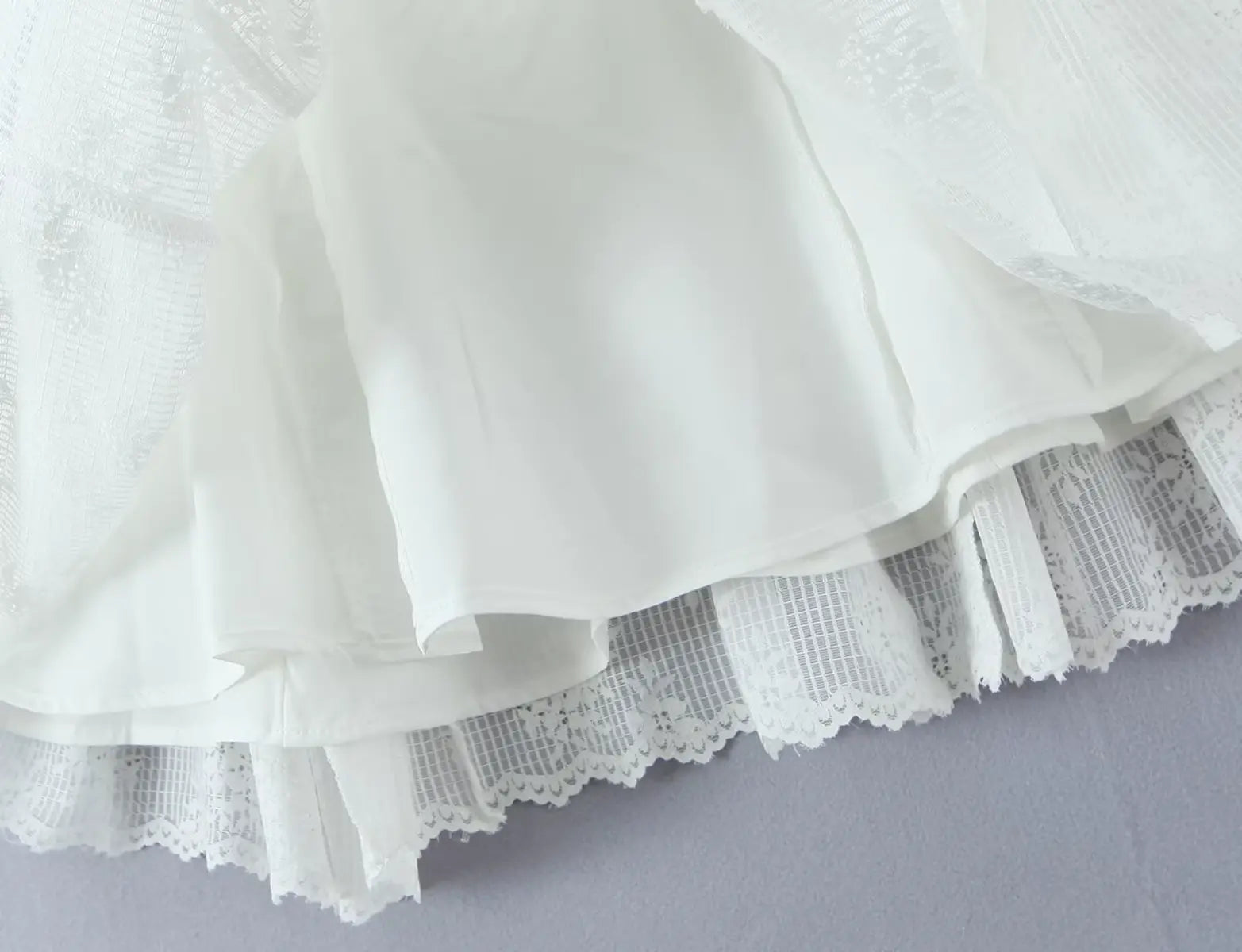 Layered ruffled hem detail of white lace halter mini dress