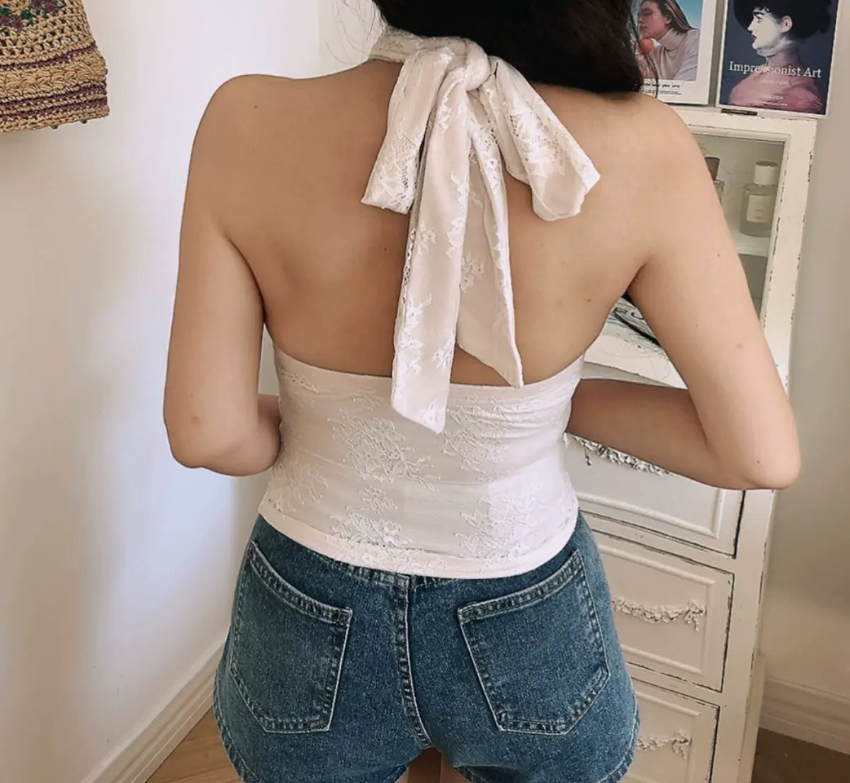 Back view of white lace halter top with tied bow closure and open back design
