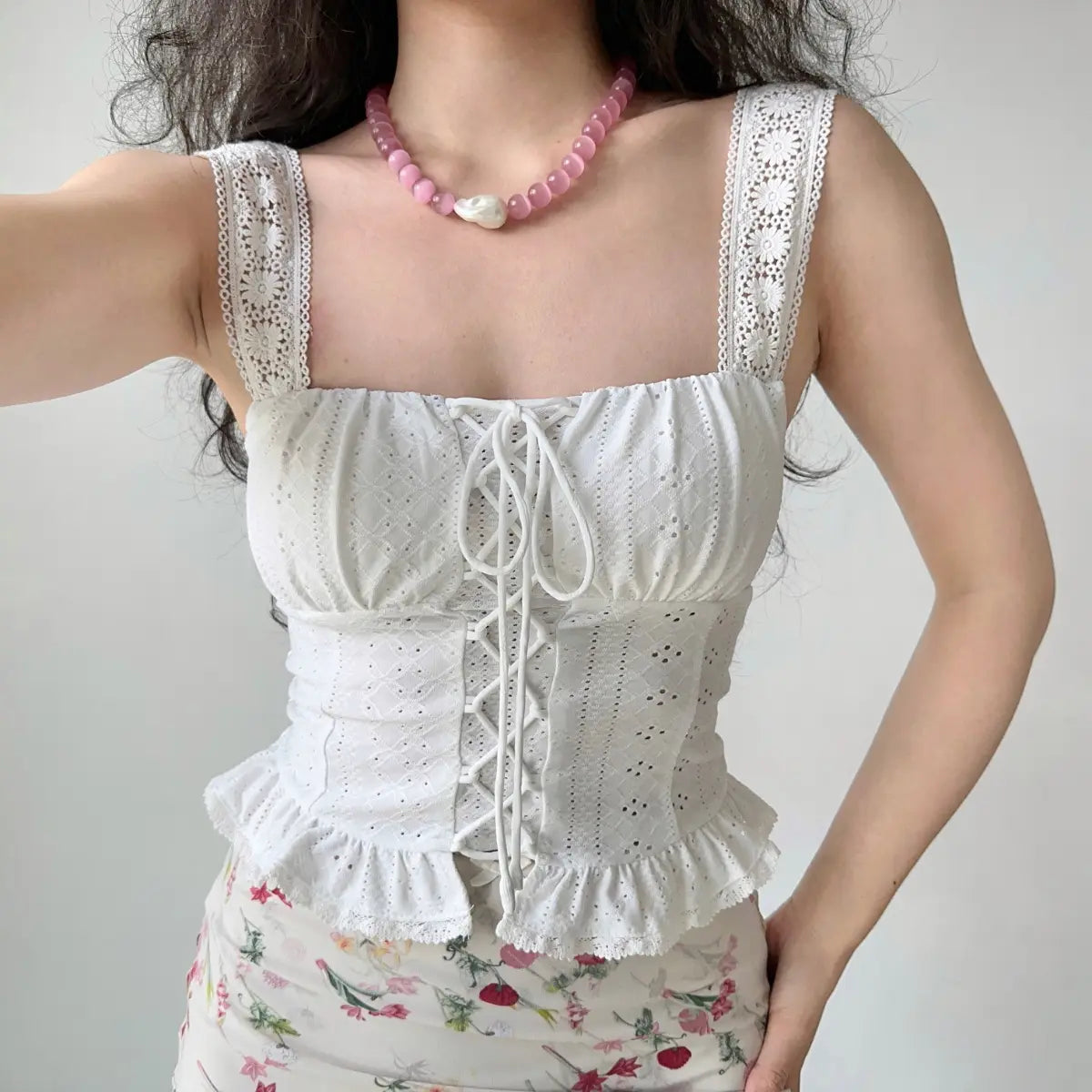 Close-up of model wearing white lace eyelet lace-up cami top