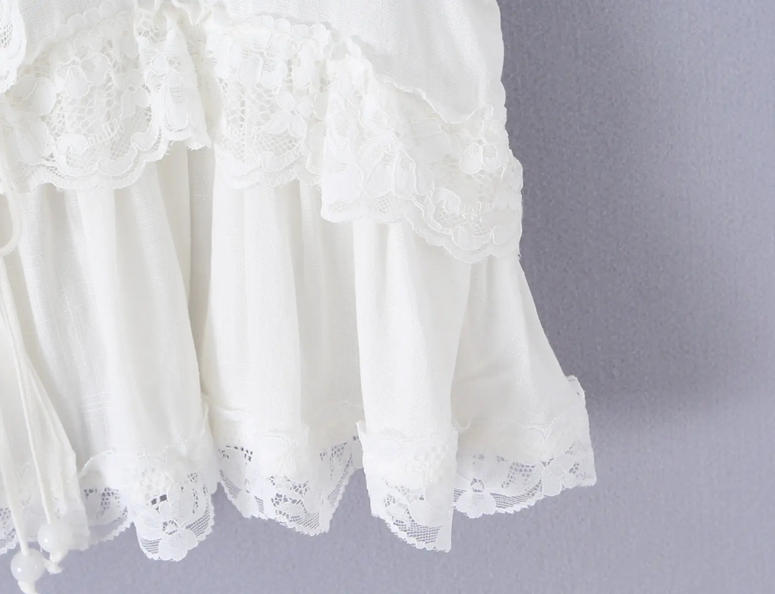 Close-up of the lace-trimmed peplum hem on the white sleeveless top, showing layered ruffles