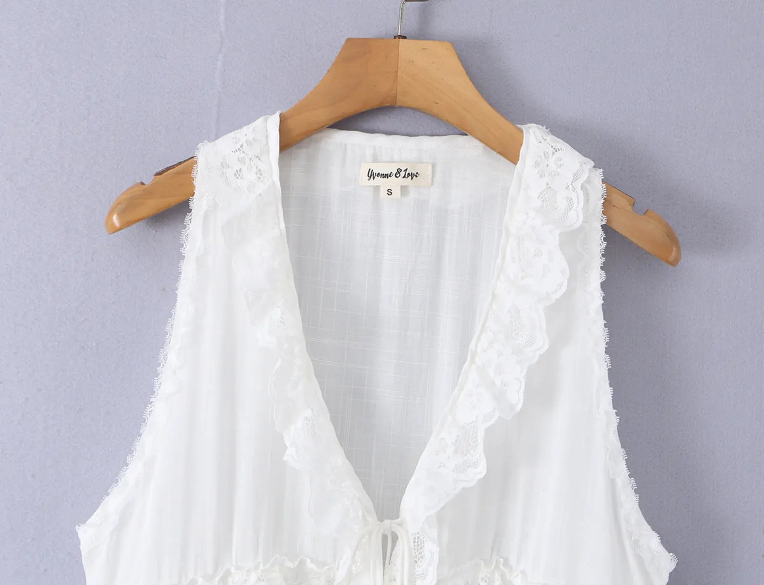 Close-up of the inner neck label and lace trim at the V-neckline of the white top