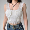 Model wearing white lace-trim cami top with heart embroidery, romantic cropped bustier-style top