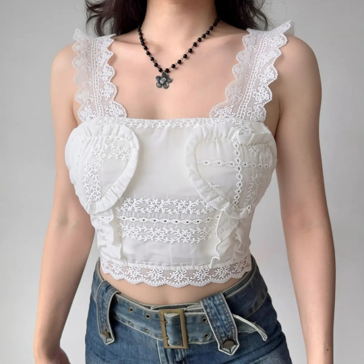 Model wearing white lace-trim cami top with heart embroidery, romantic cropped bustier-style top