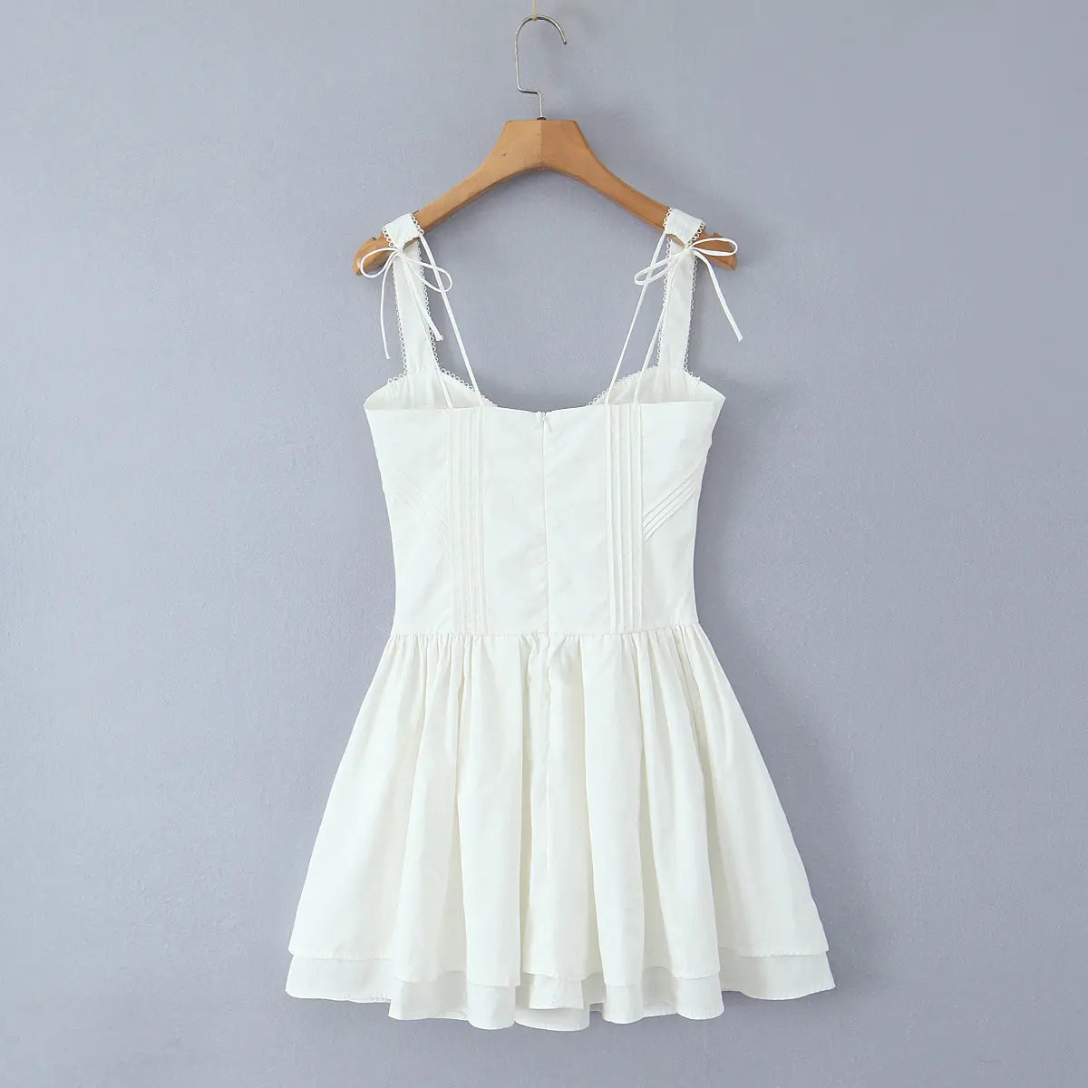 Back view of white lace-up corset cami dress on wooden hanger