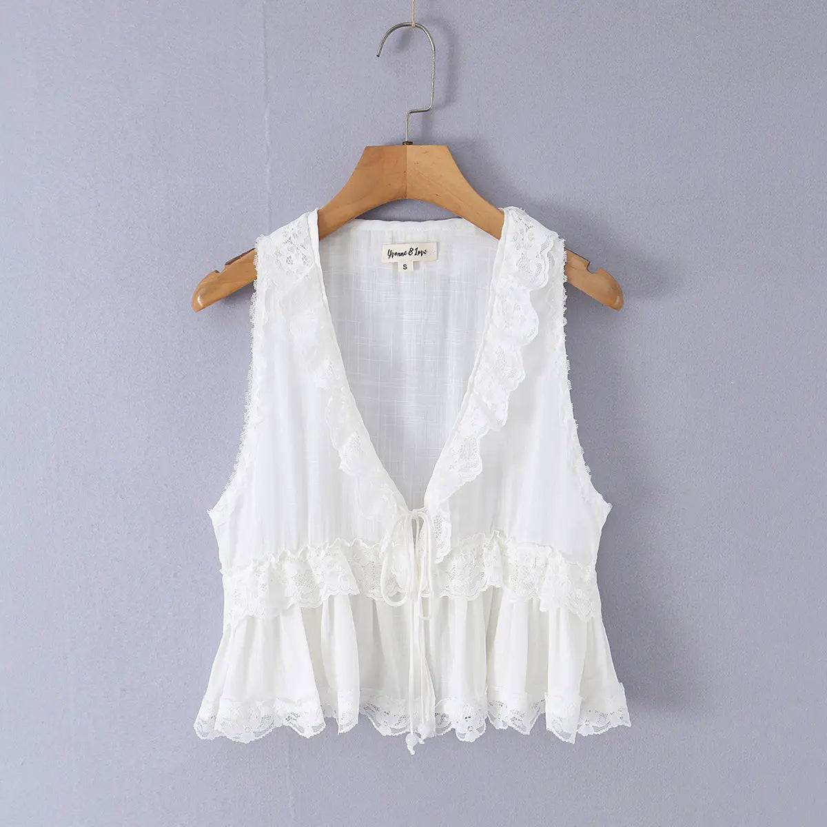 White lace-trimmed V-neck sleeveless top hanging on wooden hanger, front view