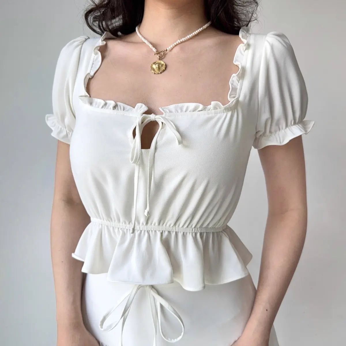 Close-up of white peplum top with keyhole tie