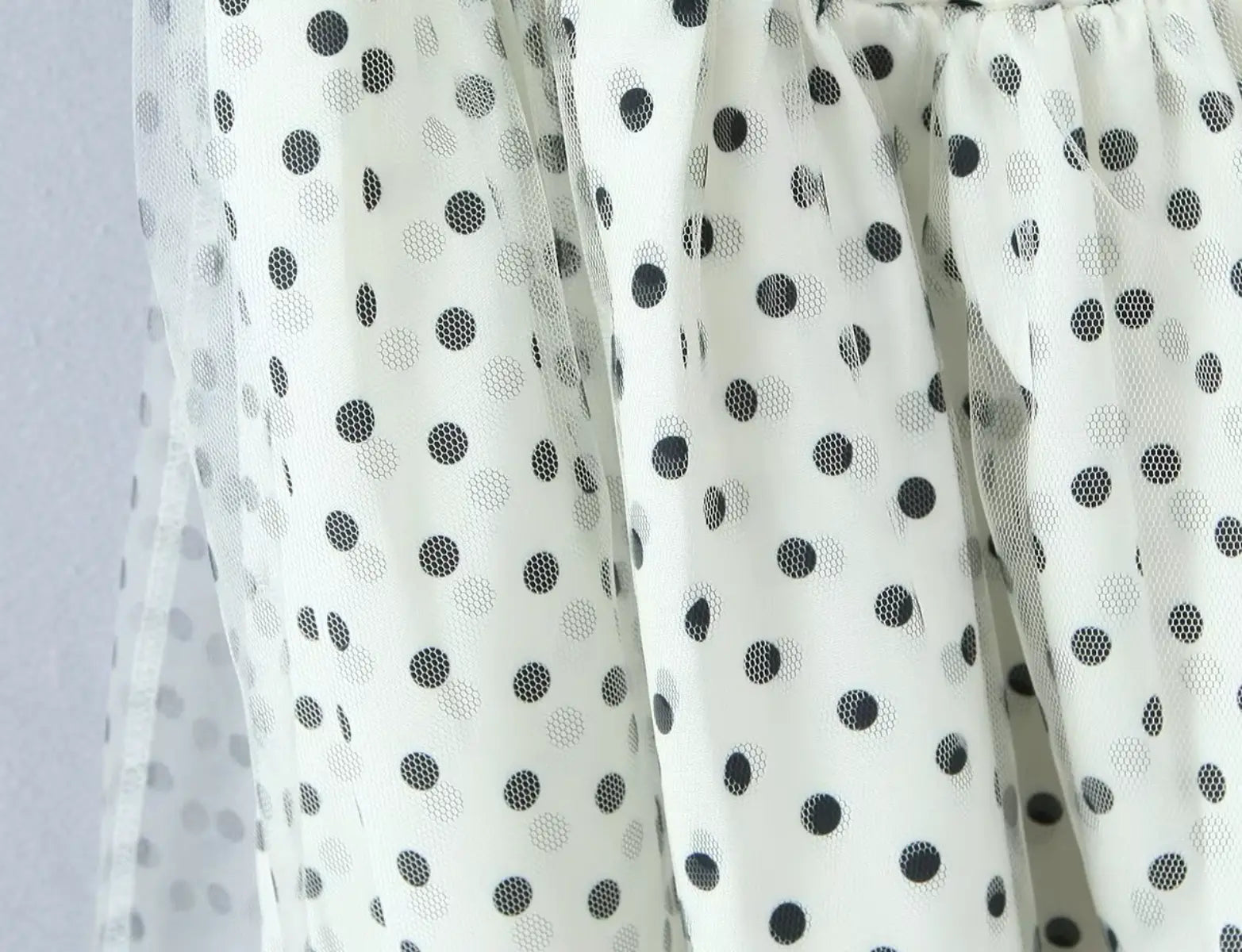 Layered tulle hem and fabric texture detail of white polka dot halter dress