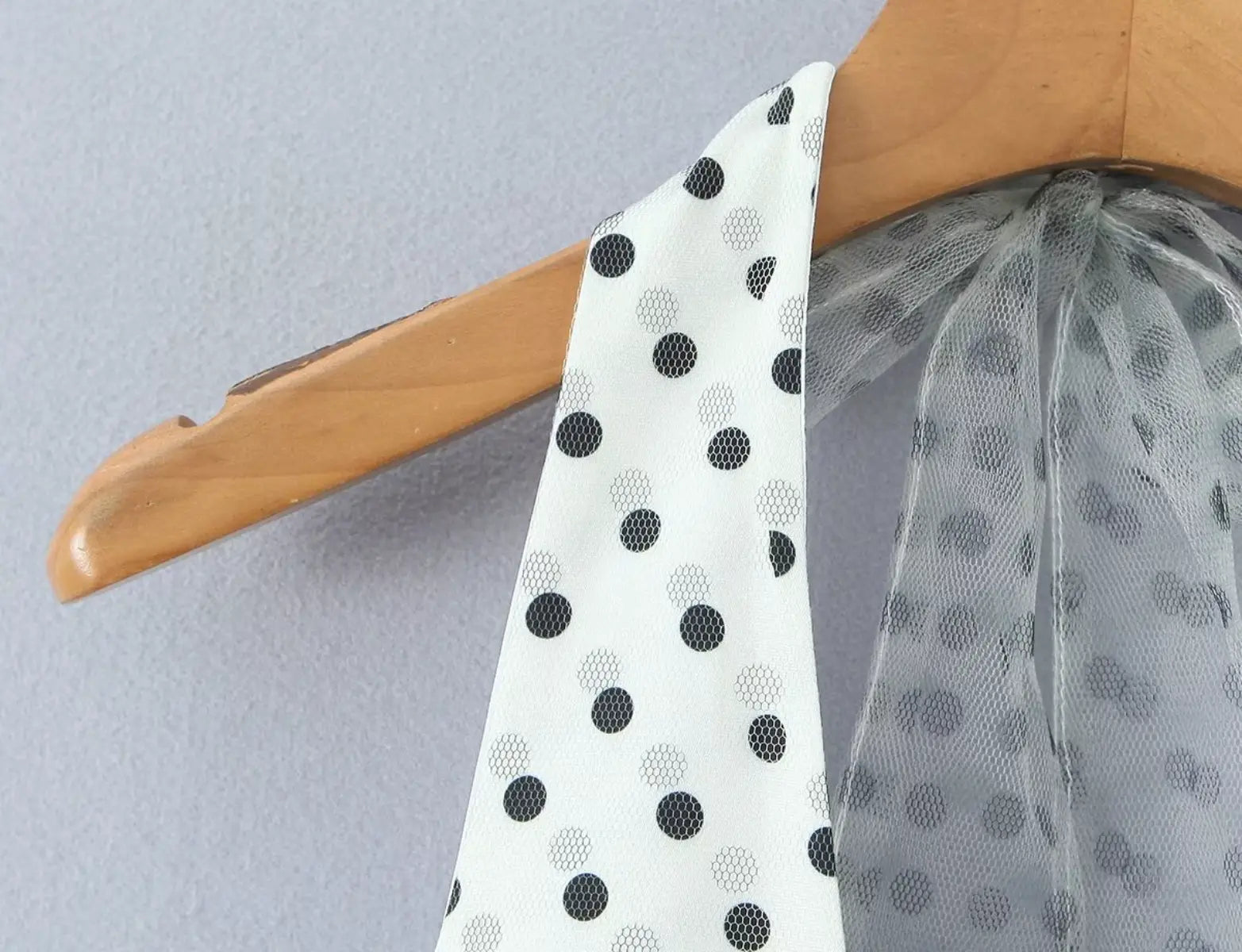 Halter neckline and tie closure detail of white polka dot mini dress