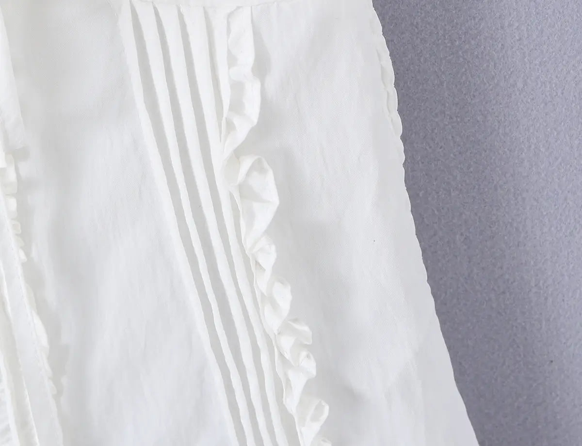 Close-up of vertical pleats and ruffled trim on the white corset-style cami top