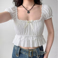 Model wearing white square-neck puff-sleeve cropped top with bow detail, cottagecore-inspired ruffle blouse
