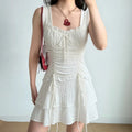 Model wearing white textured drawstring cami mini dress with tiered ruffle hem, feminine summer dress