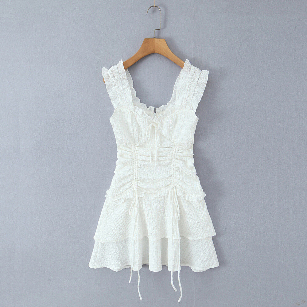 Front hanging view white textured ruffle-strap tiered mini dress with bow detail, romantic feminine summer dress