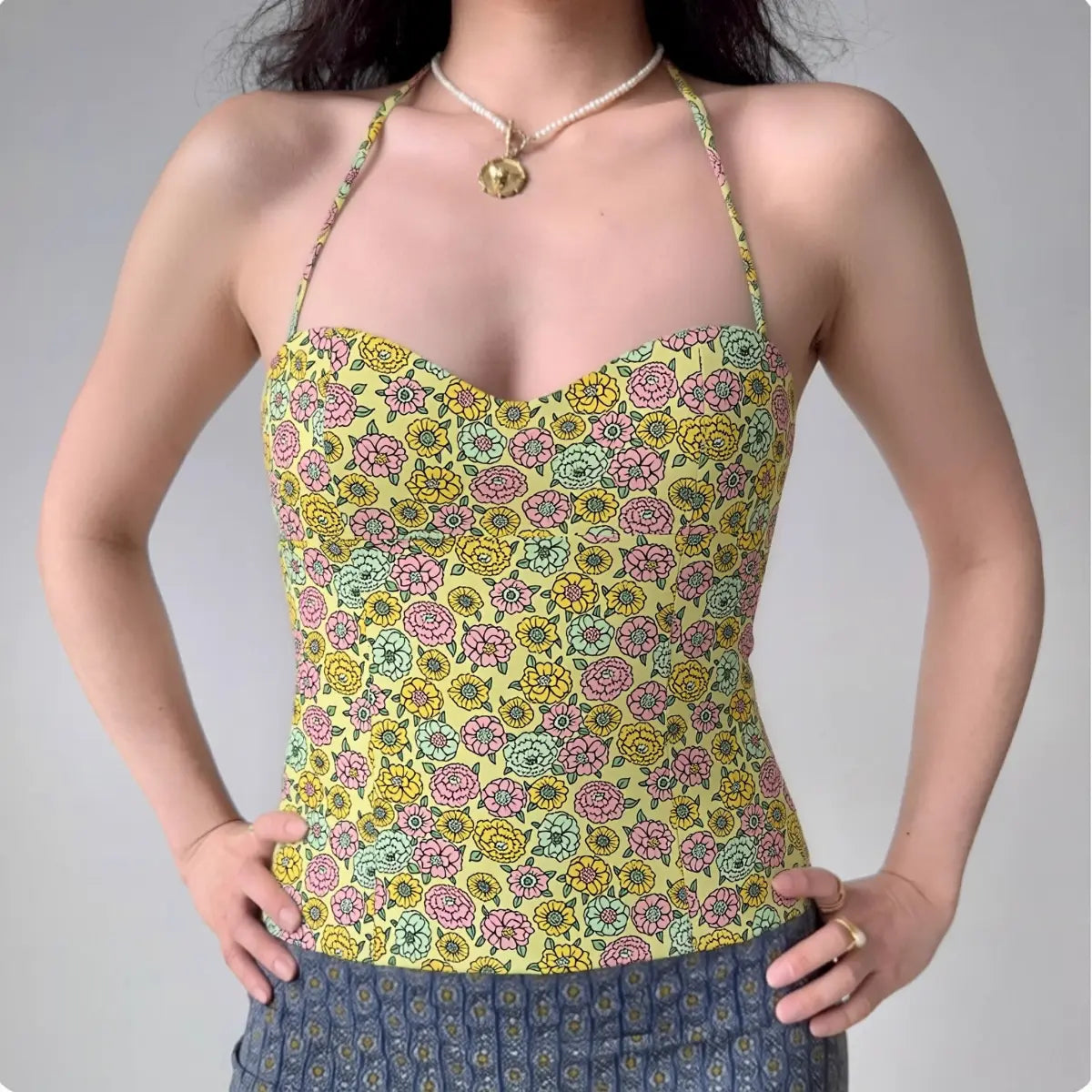 Model wearing yellow green floral halter-neck corset top with sweetheart neckline, form-fitting bustier tank