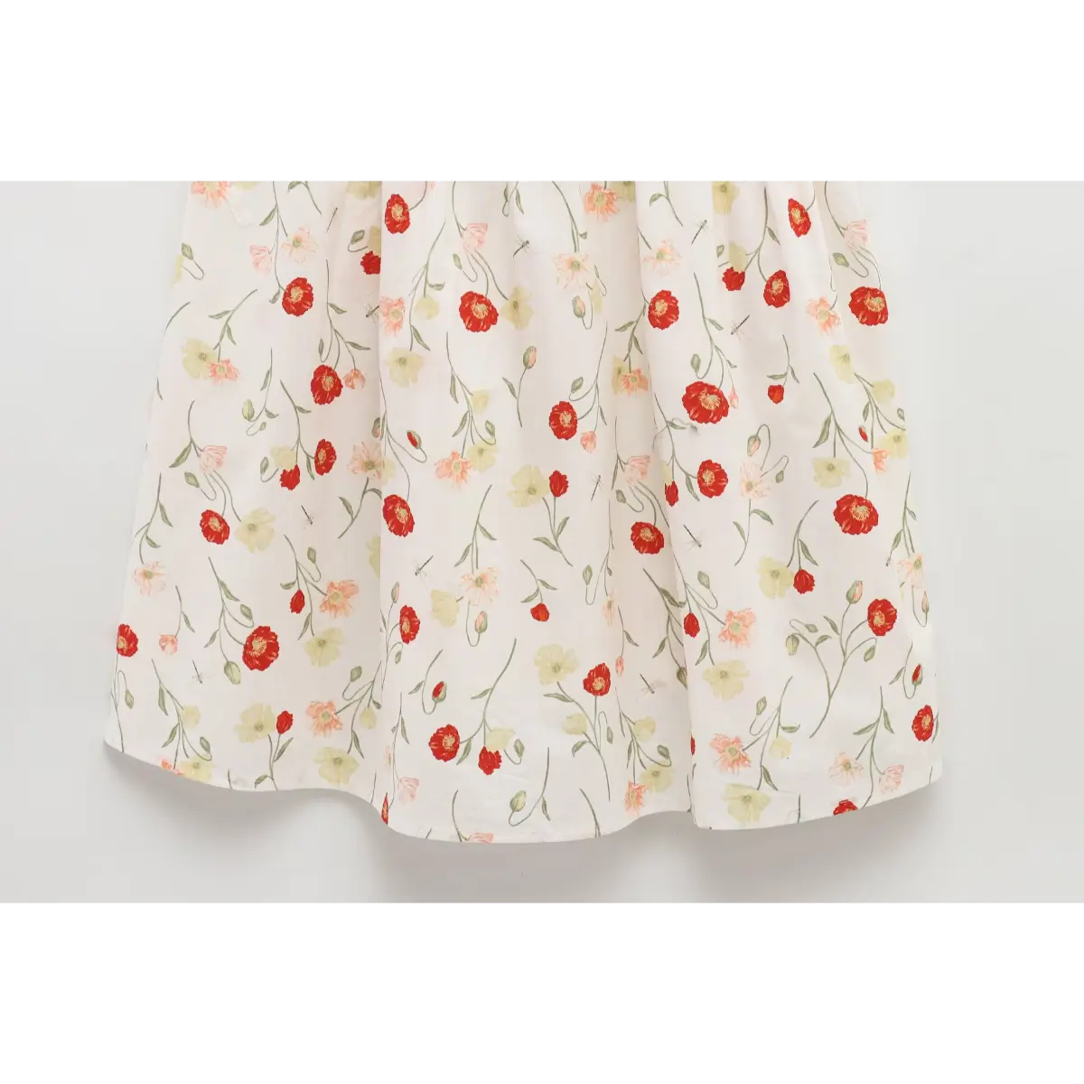 Close-up of the A-line skirt on a white poppy-print dress, highlighting the all-over floral pattern.
