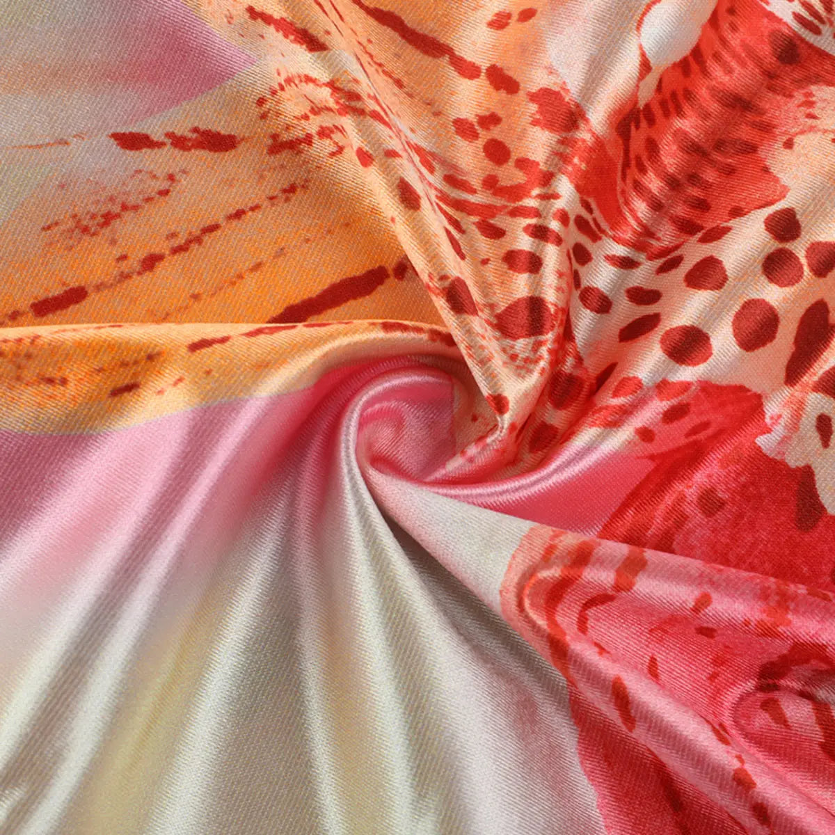 Close-up of the abstract print satin dress fabric, showing the pink/orange/red watercolor-inspired design and smooth, shiny texture