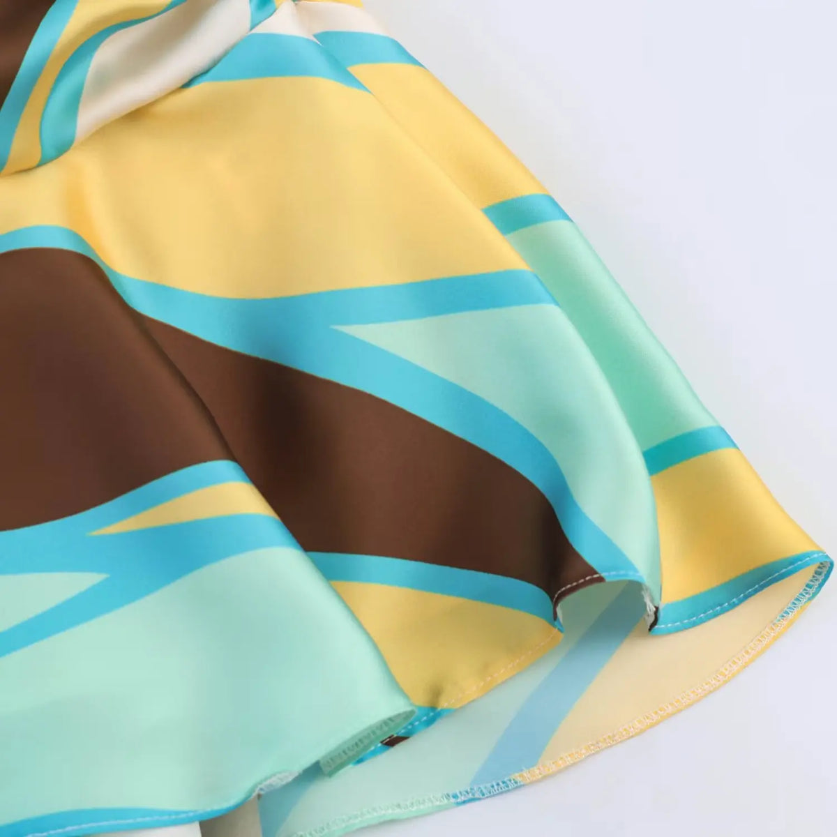 Close‑up of ruffle hem, abstract geometric print satin mini dress, finished stitching detail