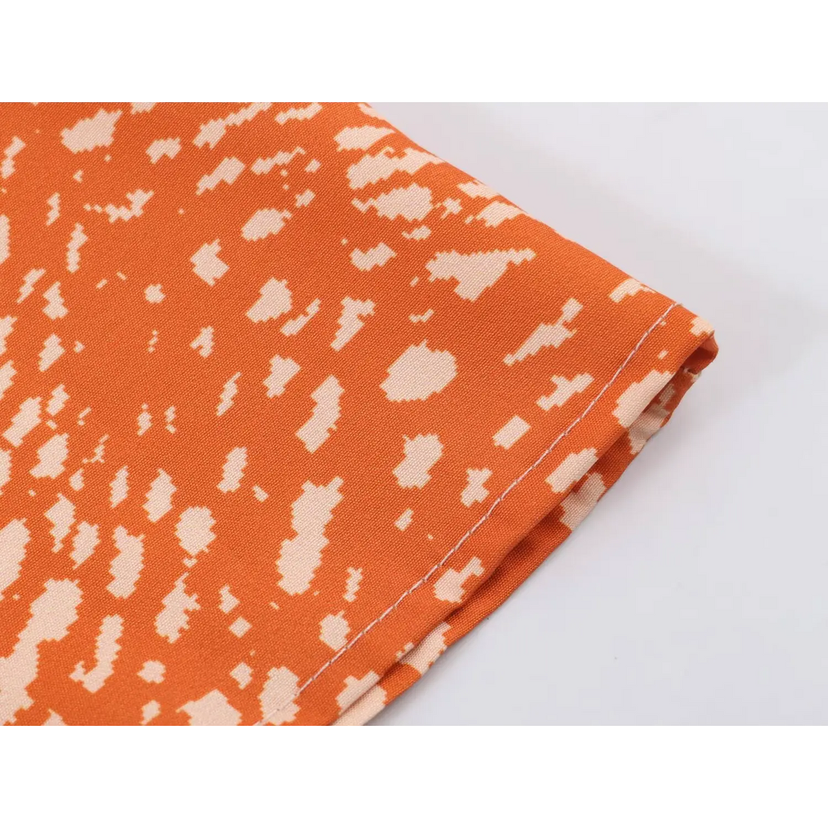 Close-up of fabric edge and stitching on orange abstract print maxi dress