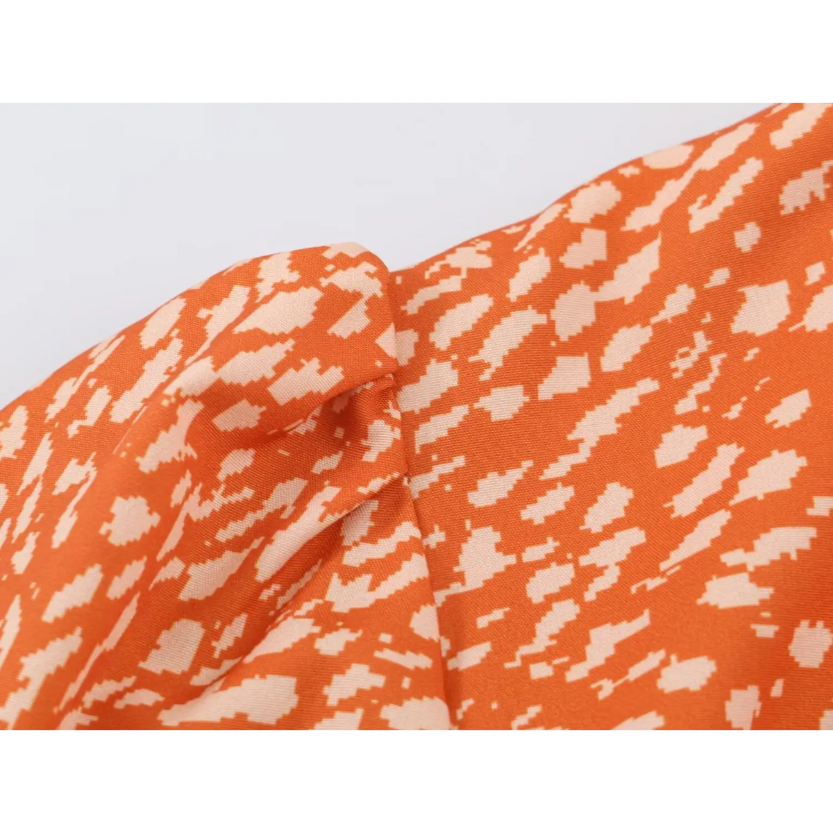 Macro shot of fabric texture for orange abstract speckled print maxi dress, showing soft drape