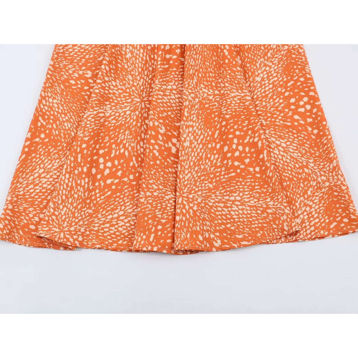 Overhead shot of flowy ruffle hem for orange abstract speckled print maxi dress