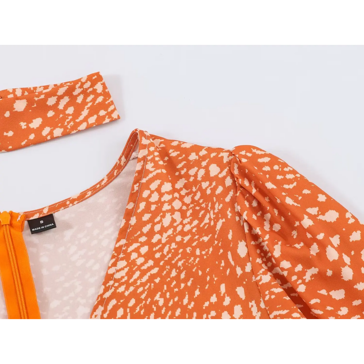 Close-up of shoulder puff detail and matching choker accessory of orange abstract speckled print maxi dress