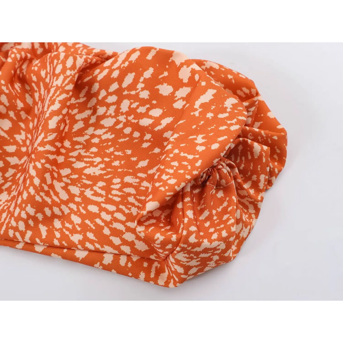 Close-up of gathered sleeve detail on abstract print maxi dress, orange base with off-white speckled pattern